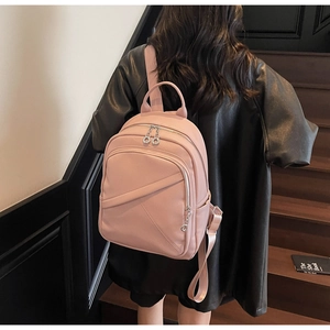 Pink lychee grain leather backpack with geometric stitching worn by a model on stairs