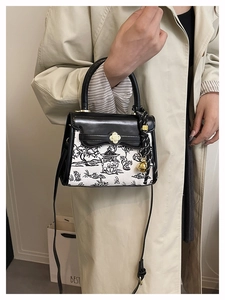Detail of crossbody bag featuring ink landscape print and golden floral metal clasp