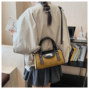 Détail d'un sac bowling vintage en daim moutarde avec garnitures en cuir noir