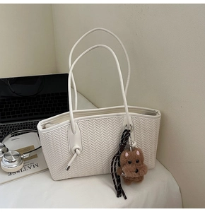 Sac cabas blanc tressé avec breloque chien en peluche sur un bureau moderne