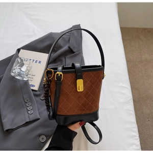 Detail view of retro brown quilted suede bucket bag with gold lock and silk scarf accessory