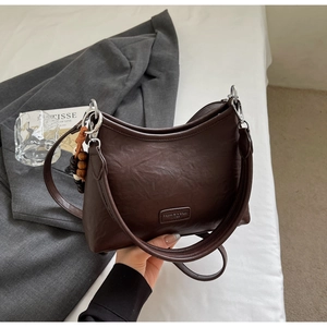 Detail of vintage brown leather bag featuring wood bead tassel and fashion label