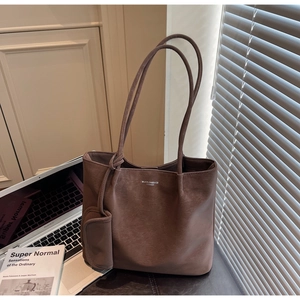 Detailed shot of dark brown leather tote bag with brand logo and side accessory pouch