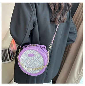 Detail of round purple crossbody bag featuring pearl decor and geometric jacquard texture