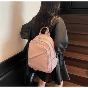 Pink pebbled leather backpack shown on a model's back while standing on wooden stairs