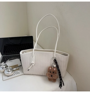 Détail du sac fourre-tout tressé blanc avec charm ours brun et longue bandoulière fine