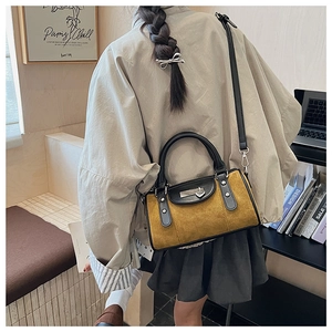 Détail du sac seau en daim jaune avec poignées noires et pendentif en forme de cœur
