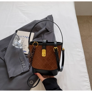 Detail of brown quilted suede bucket bag with gold clasp and elegant tassel