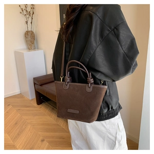 Dettaglio mini borsa tote in pelle scamosciata con manico annodato ed etichetta logo
