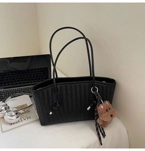 Détail d'un cabas noir tressé avec pendentif chien en peluche et fermeture éclair métallique