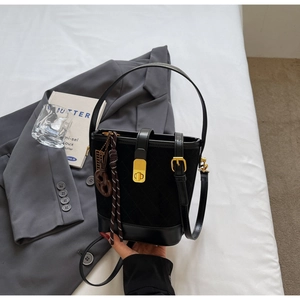 Detail of black quilted bucket bag featuring a gold twist lock and a suede-like texture