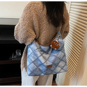 Detail of a denim tote bag with plush charm and matching coin purse on a model