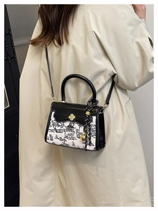 Detail of vintage landscape print crossbody bag with golden floral clasp and bell charm