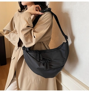 Detail der schwarzen Nylon-Tasche mit Falten-Design und gewebten Seil-Reißverschlusszügen