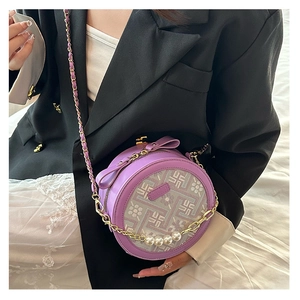 Detail of purple circular crossbody bag with pearl handle and butterfly bow accent