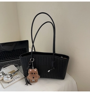 Détail du sac cabas tissé noir avec breloque ours en peluche et ruban rayé élégant