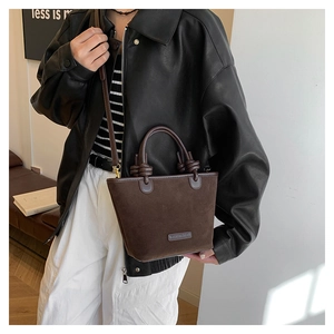 Detail shot of coffee brown suede bucket bag featuring knotted handle and shoulder strap
