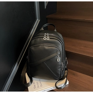 Close-up of black litchi leather backpack with multiple zippers and silver metal pullers