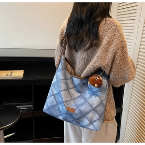 Rear view of a model wearing a quilted denim bucket bag with plush charm and round pouch