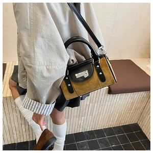 Détail du sac seau en daim jaune moutarde avec poignée en cuir noir et garniture élégante