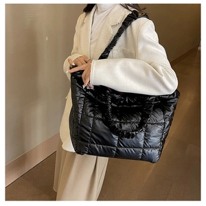 Side view of large black quilted puffer tote bag with wide pleated shoulder strap