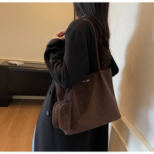 Detail of dark brown matte tote bag featuring a long shoulder strap and matching coin pouch