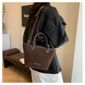 Borsa a secchiello in pelle scamosciata marrone scuro indossata da una modella