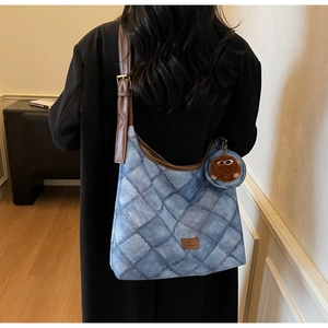 Detail of blue quilted shoulder bag with brown strap and plush eye charm accessory