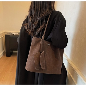 Detail view of a large dark brown faux suede tote bag with a matching small pouch
