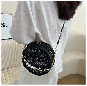 Detail showing the exquisite embroidery and pearl chain of this round crossbody bag