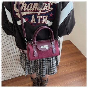 Détails du sac seau bordeaux avec clous argentés, cadenas cœur et textures mixtes