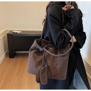 Detail of vintage brown suede tote bag with slim straps and small matching pouch charm