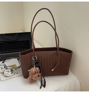 Détail du sac cabas marron tissé avec charm chien en peluche et ruban décoratif