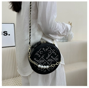 Detail of black round crossbody bag with floral embroidery and elegant pearl chain