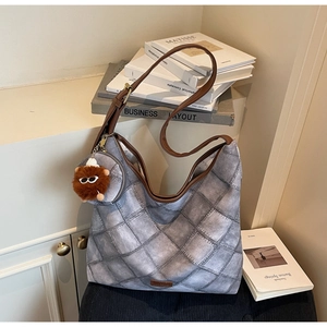 Detail of grey quilted hobo bag featuring leather straps and trendy plush doll accessory