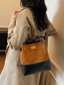 Vintage suede bucket bag with black quilted leather and gold chain strap on a model