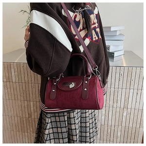 Détail du sac Boston bordeaux avec boucle cœur argentée et rivets porté par un mannequin