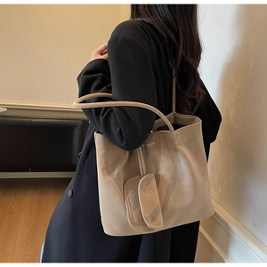Detail of a beige suede tote bag with minimalist lettering and a matching small pouch