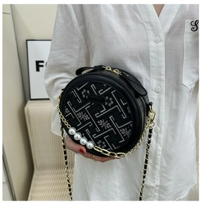 Close-up of black round bag featuring floral embroidery, gold chains and large pearls