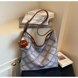 Close-up of gray quilted hobo bag with denim print, leather strap, and mini pouch accessory
