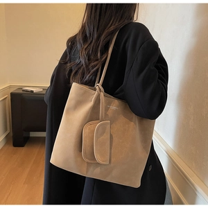 Large khaki tote bag with a small matching pouch shown on a shoulder in a high-quality lifestyle shot