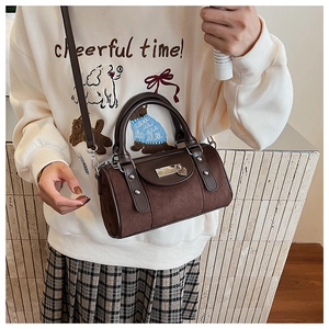 Détail d'un sac seau en daim marron avec poignées en cuir et boucle en métal vintage