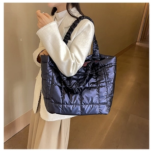 Detail view of large quilted puffer tote bag with glossy finish and ruched shoulder strap