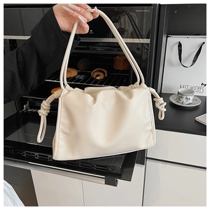 Detail der cremeweißen Handtasche aus gerafftem Leder mit dekorativem Knoten am Schultergurt