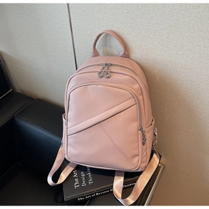 Close-up of pink lychee leather texture and silver zipper detail on the travel backpack