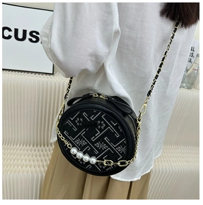 Detail of black round crossbody bag with geometric embroidery and pearl accents