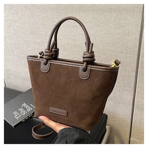 Dettaglio borsa tote in pelle scamosciata marrone con manico a nodo e logo in pelle