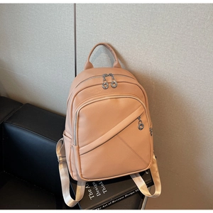 Close-up of pink pebbled leather backpack with silver zippers and cream fabric straps