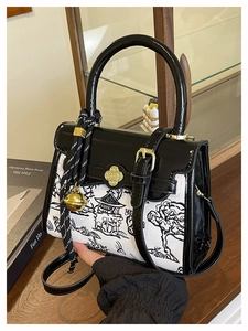 Detail of a chic crossbody bag with Chinese ink painting and golden clover clasp closure