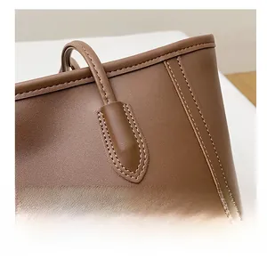 Close-up of double stitching detail and litchi grain leather on a brown tote bag